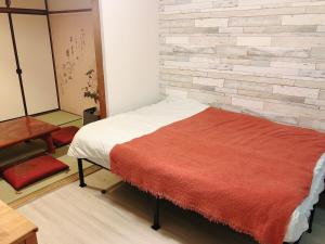 a bedroom with a bed with a brick wall at Station Front JUSO EAST 402 No Lift in Osaka