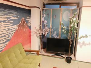 a living room with a tv and flowers on the wall at Station Front JUSO EAST 402 No Lift in Osaka