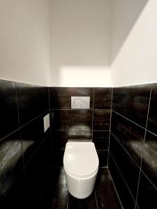 baño con aseo blanco en una pared de azulejos negros en Cozy Apartment in Zeltweg for MotoGP, en Zeltweg