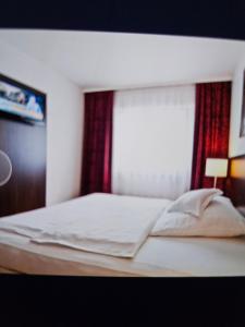 a bedroom with a white bed with a red curtain at Hotel&Spa am Oppspring in Mülheim an der Ruhr