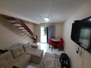 a living room with a couch and a table with red chairs at Casa 2qts Churrasqueira Condomínio Pássaros Peró in Cabo Frio