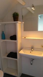 La salle de bains est pourvue d'un lavabo et d'un miroir. dans l'établissement B&B Duinroos De Koog - Texel, à De Koog