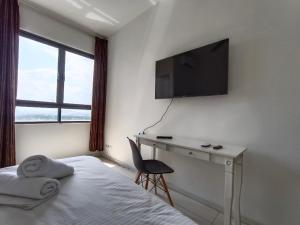 a bedroom with a bed and a desk and a television at Peacehome horizon in Kampong Melot