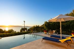a swimming pool with an umbrella and two lounge chairs and an umbrella at Am Meer Suite in Argostoli