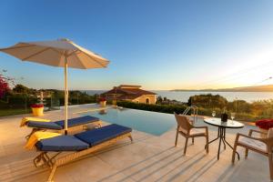 a swimming pool with two lounge chairs and an umbrella at Am Meer Suite in Argostoli