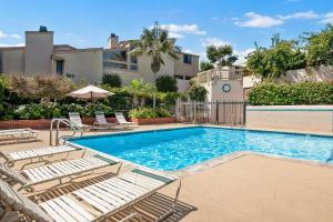 a swimming pool with lounge chairs next to a building at Tranquil Living - SUR4 in Solana Beach