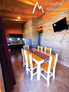 Un comedor con una mesa y sillas blancas. en Cabañas Almafuerte, en Villa Quillinzo