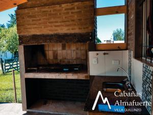 an outdoor kitchen with a brick wall and a stove at Cabañas Almafuerte in Villa Quillinzo