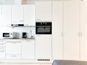 a white kitchen with white cabinets and a microwave at Apartment Kruuna in Kuopio