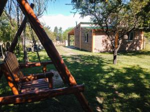 a wooden swing in a yard with a house at Cabañas Almafuerte in Villa Quillinzo