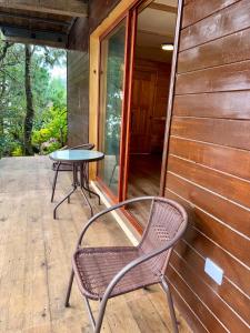 a chair and a table on the porch of a house at San José del Pacífico- Cabañas Camino al Cielo 2 in San Mateo Río Hondo