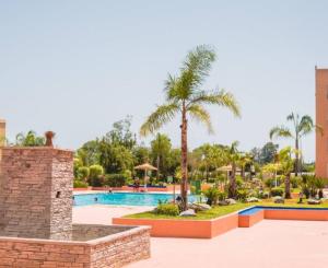 a resort with a swimming pool and palm trees at Ricoflores PALM in Ben Slimane
