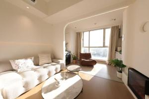 a living room with a white couch and a tv at Shanghai Hills & Wanda Side Spacious Stay Close to Metro Line 18 in Shanghai