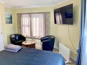 a bedroom with a blue bed and chairs and a table at Hillcrest One in Whakatane