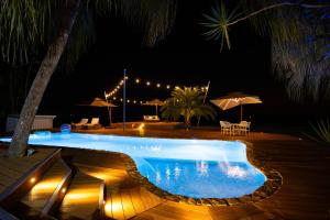 a swimming pool at night with chairs and umbrellas at Paradis Sur Terre Ocean View Fiji Villa for 12 with 2 Private Pools in Lauwaki