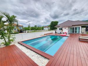 a swimming pool on a wooden deck next to a house at Pool Villa - Phetchabun in Ban Yawi