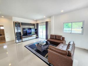 a living room with a leather couch and a table at Pool Villa - Phetchabun in Ban Yawi