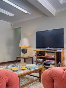 a living room with two chairs and a large television at Araucária Lodge - 800 metros do Capivari in Campos do Jordão +125 photos