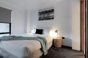 City Retreat with Parking في لونسيستون: غرفة نوم بيضاء فيها سرير ومصباح