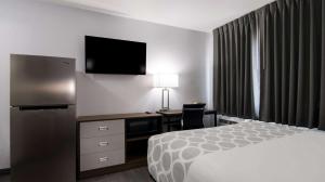 a hotel room with a bed and a desk with a television at Suburban Studios Portage in Portage