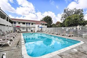 a swimming pool with chairs and a fence at Super 8 by Wyndham Petaluma in Petaluma