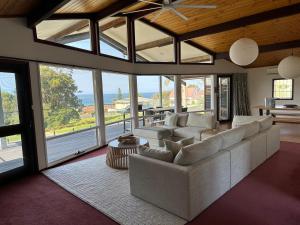 a living room with a couch and chairs and windows at Eden Niu in Eden