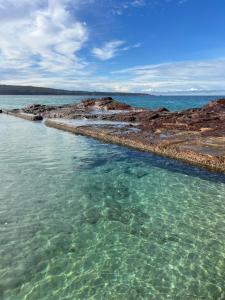 a large body of water with a rocky shore at Eden Niu in Eden +7 photos