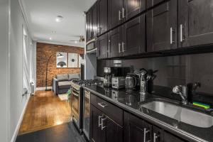 a kitchen with black cabinets and a living room at Modern Manhattan Retreat Near Central Park in New York