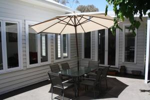 a table and chairs with an umbrella on a patio at Spacious self contained house walking distance-CBD in Bendigo
