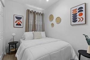 坦帕Boho Inspired Apt in the heart of Tampa Bay!的白色卧室配有一张床,墙上挂有绘画作品