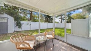a porch with wicker chairs and a table and a fence at Comfy Modern Farmhouse Cottage w/ Private Patio! in Tampa