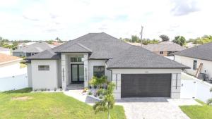 une grande maison blanche avec un garage dans l'établissement Breezy Coral Escape-Heated Pool, à Cape Coral
