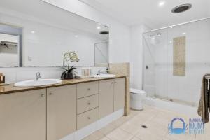 a bathroom with two sinks and a shower and a toilet at Coastal Canal Retreat in Mandurah in Mandurah