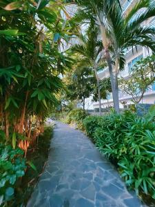 a walkway through a resort with palm trees at Aveline Suites Luna,1br, balcony & amenities in Manila