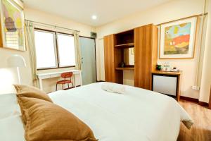 a bedroom with a large white bed and two windows at Thong Poon Apartment Chiang Mai in Chiang Mai