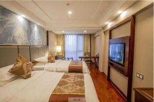 a hotel room with two beds and a flat screen tv at GreenTree Eastern Hotel Linyi Linshu County Aegean Sea in Linyi +210 photos