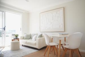 a living room with a white couch and a table at Diggers Beach Villa Coffs Harbour in Coffs Harbour