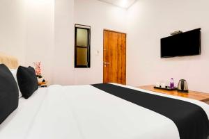 a bedroom with a white bed and a flat screen tv at Collection O Pardi Near Kalamna Market in Nagpur