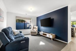 a blue living room with a couch and a tv at Family-Friendly 4BR Mount Duneed Manor in Mount Duneed