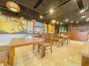 a restaurant with tables and chairs and a large painting on the wall at Azumaya Hotel Dao Tan in Hanoi