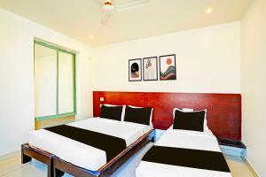 two beds in a room with a red headboard at Collection O Kaveri Road Mysore in Mysore