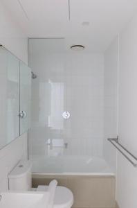 a white bathroom with a toilet and a shower at The Clocktower Light and Airy Studio on Bourke St in Melbourne +28 photos