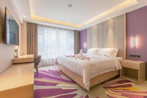 a bedroom with a large bed and a purple wall at Lavande Hotel Wuhan Houhu Avenue Xingye Road in Wuhan