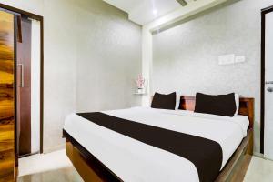 a bedroom with a large white bed with black pillows at Collection O Wardha Road Near Airport in Nagpur
