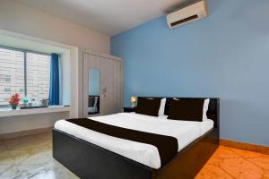 a bedroom with a large bed with a blue wall at Collection O Dumduma Near DN Regalia Mall in Bhubaneshwar