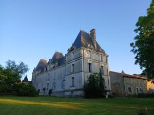 an old house with a tower on a grass field at Chambres d'Hôtes Bienvenue in LʼAbsie