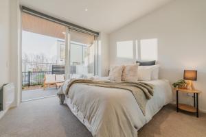 Un dormitorio con una cama grande y una ventana grande en Central 1BR Apartment with Kitchen & Patio, en Christchurch