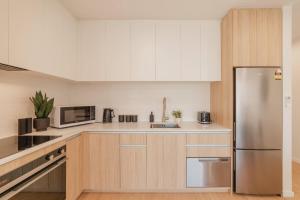 Una cocina con gabinetes blancos y un refrigerador de acero inoxidable. en Central 1BR Apartment with Kitchen & Patio, en Christchurch