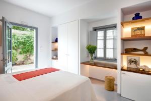 a white bedroom with a bed and a window at Orloff Resort in Spetses