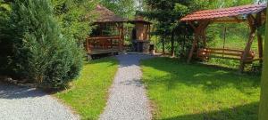 a path in a garden with benches and a gazebo at Csergő Kulcsosház in Senetea